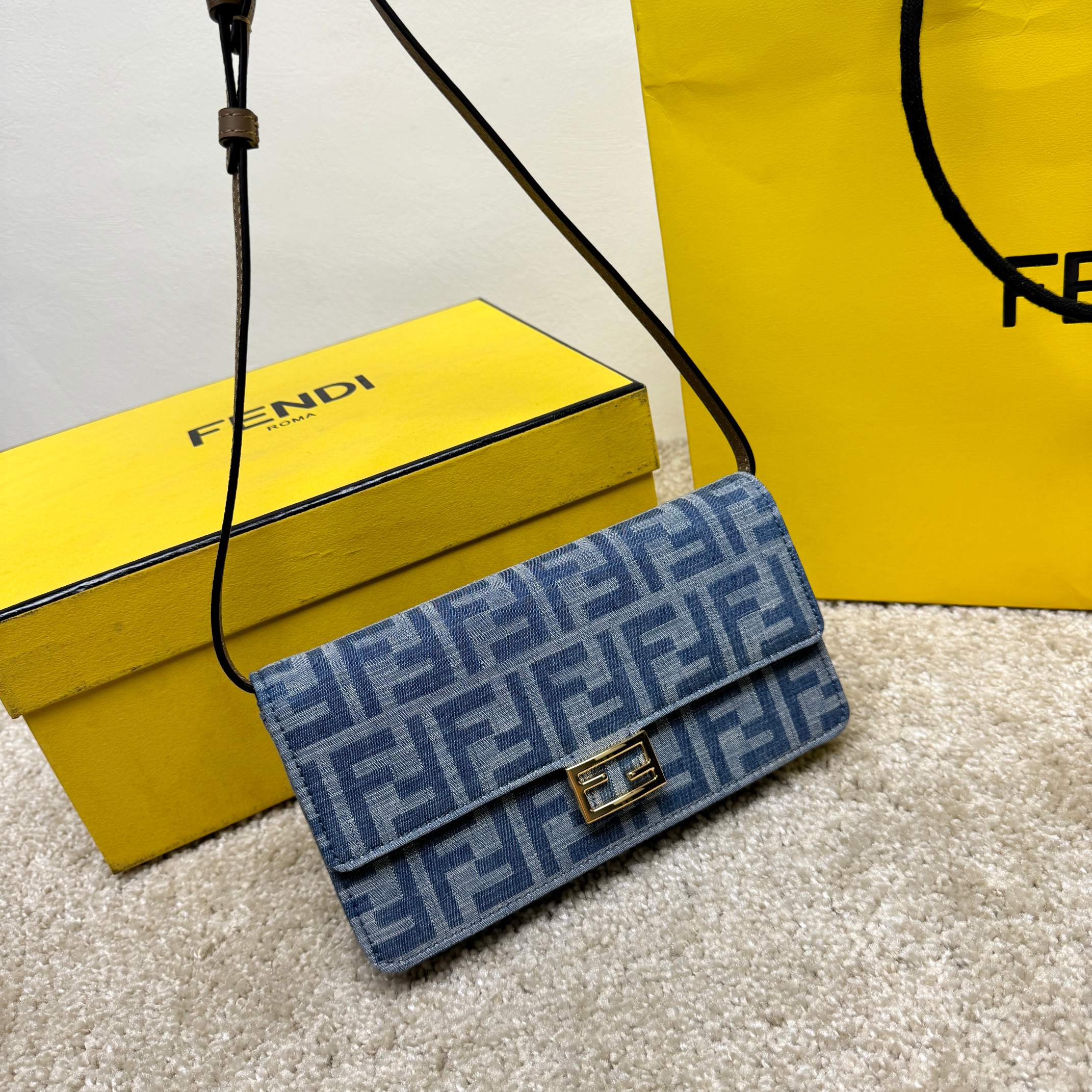 Compact Baguette wallet with flap and FF buckle. The internal compartment has six card slots. Two shoulder straps, including an adjustable leather strap, and a removable thin chain strap: hand-held, armpit-carrying or cross-body. Jacquard denim with signature light blue FF pattern. Beige leather details. Gold finish metal parts. Model: 9916 denim orchid Size: 21-11.5-5cm